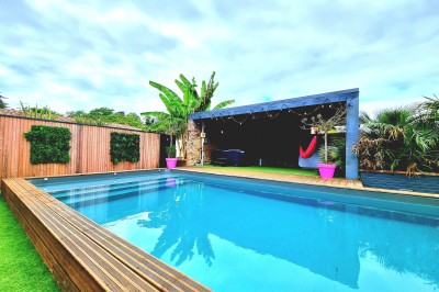 Table décorée avec des pampas et des nappes beige, installée dans un jardin avec des plantes tropicales en arrière-plan.