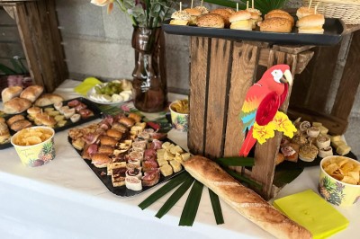 Table décorée avec des pampas et des nappes beige, installée dans un jardin avec des plantes tropicales en arrière-plan.