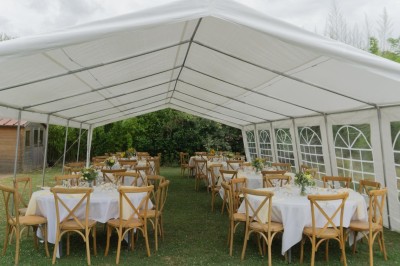 Table décorée avec des pampas et des nappes beige, installée dans un jardin avec des plantes tropicales en arrière-plan.