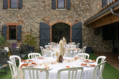 Table décorée avec des pampas et des nappes beige, installée dans un jardin avec des plantes tropicales en arrière-plan.