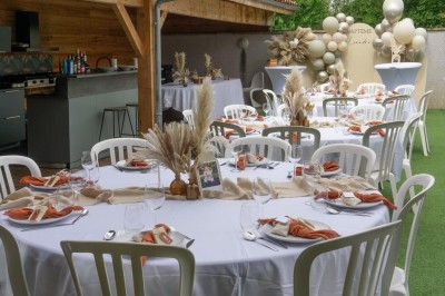 Table décorée avec des pampas et des nappes beige, installée dans un jardin avec des plantes tropicales en arrière-plan.