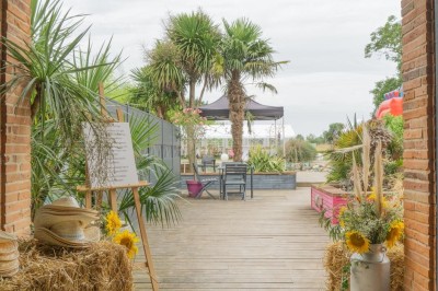 Table décorée avec des pampas et des nappes beige, installée dans un jardin avec des plantes tropicales en arrière-plan.