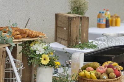 Table décorée avec des pampas et des nappes beige, installée dans un jardin avec des plantes tropicales en arrière-plan.
