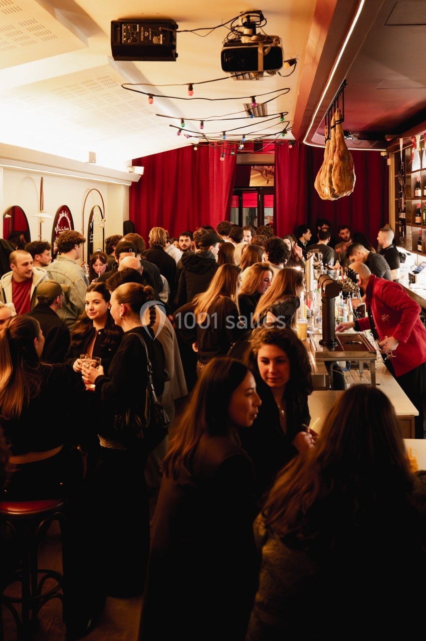Groupe de personnes discutant et partageant un moment convivial dans un bar animé avec un éclairage chaleureux.