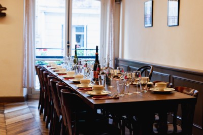 Façade d'un restaurant avec terrasse, auvent rouge et inscriptions ’Club Cochon - La Cave’ et ’Épicerie Cochonne’.
