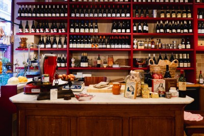 Façade d'un restaurant avec terrasse, auvent rouge et inscriptions ’Club Cochon - La Cave’ et ’Épicerie Cochonne’.