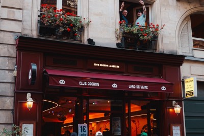 Miniature Location salle Paris 9 (Paris) - Club Cochon l'Auberge #37 Deux jeunes femmes souriantes tenant des verres, entourées de personnes dans une ambiance festive et lumineuse.