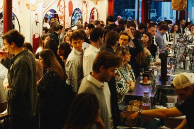 Miniature Location salle Paris 9 (Paris) - Club Cochon l'Auberge #53 Deux jeunes femmes souriantes tenant des verres, entourées de personnes dans une ambiance festive et lumineuse.