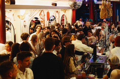 Miniature Location salle Paris 9 (Paris) - Club Cochon l'Auberge #14 Deux jeunes femmes souriantes tenant des verres, entourées de personnes dans une ambiance festive et lumineuse.
