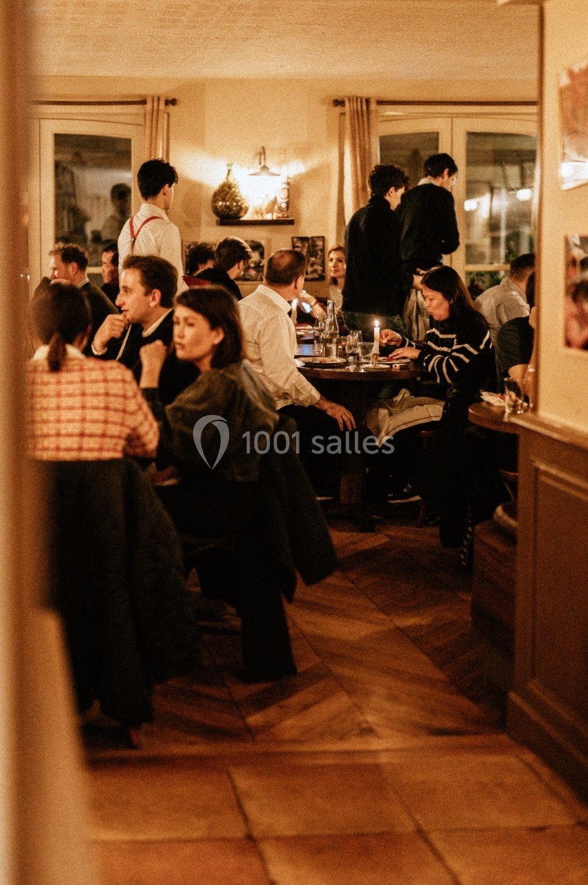Salle de restaurant animée avec des clients attablés et des serveurs en service dans une ambiance chaleureuse.
