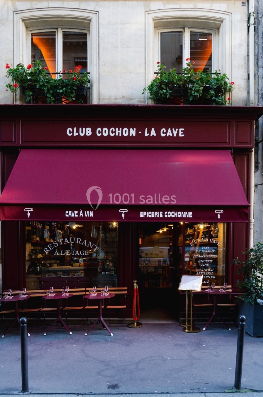 Façade d'un restaurant avec une enseigne ’Club Cochon - La Cave’, terrasse avec tables et chaises devant.