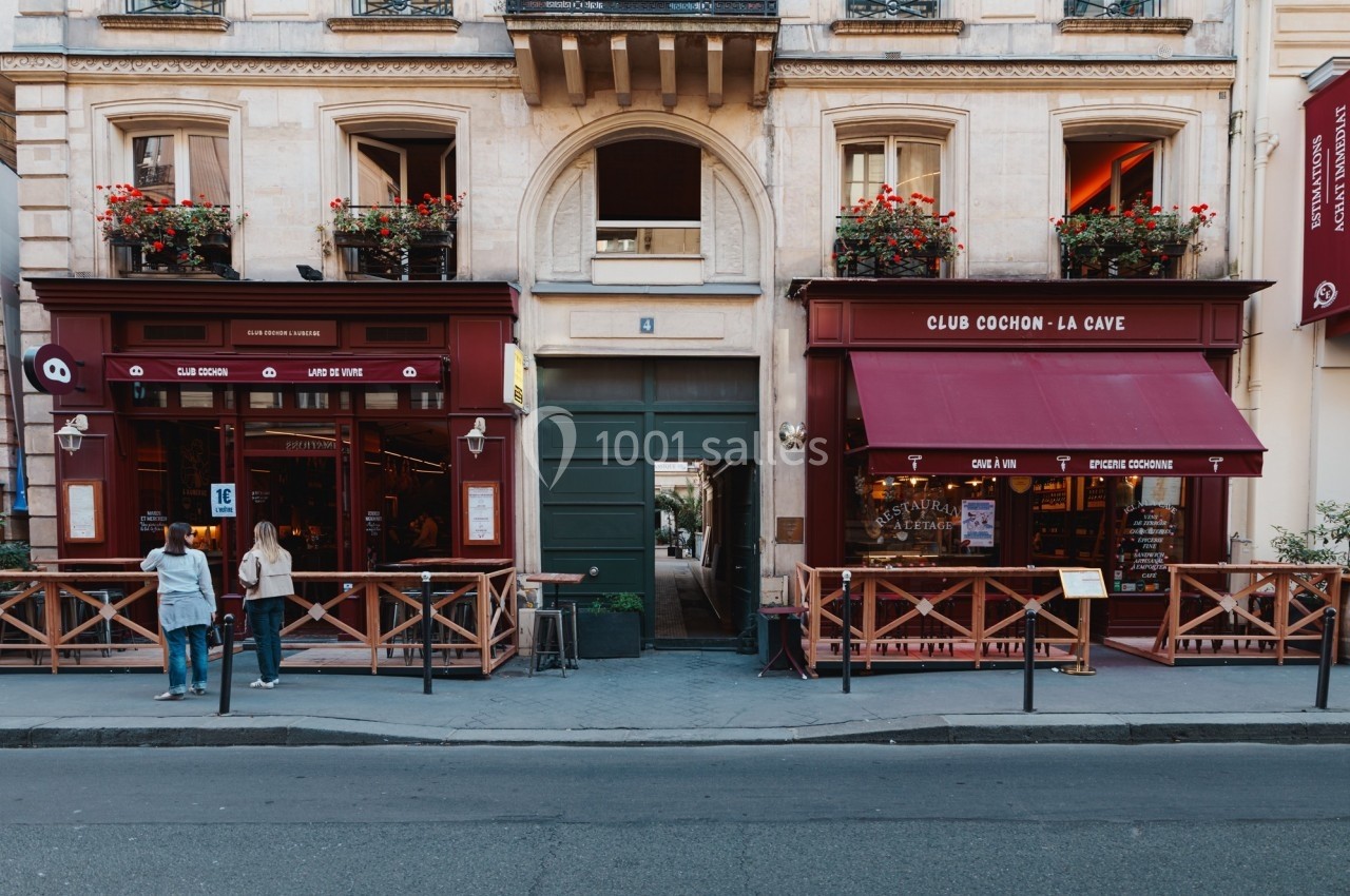 Façade de deux restaurants avec terrasses en bois, séparés par une porte cochère, dans une rue urbaine.