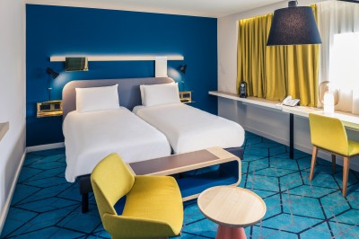 Salle de bain moderne avec baignoire, lavabo, miroir, peignoir suspendu et sol en damier noir et blanc.