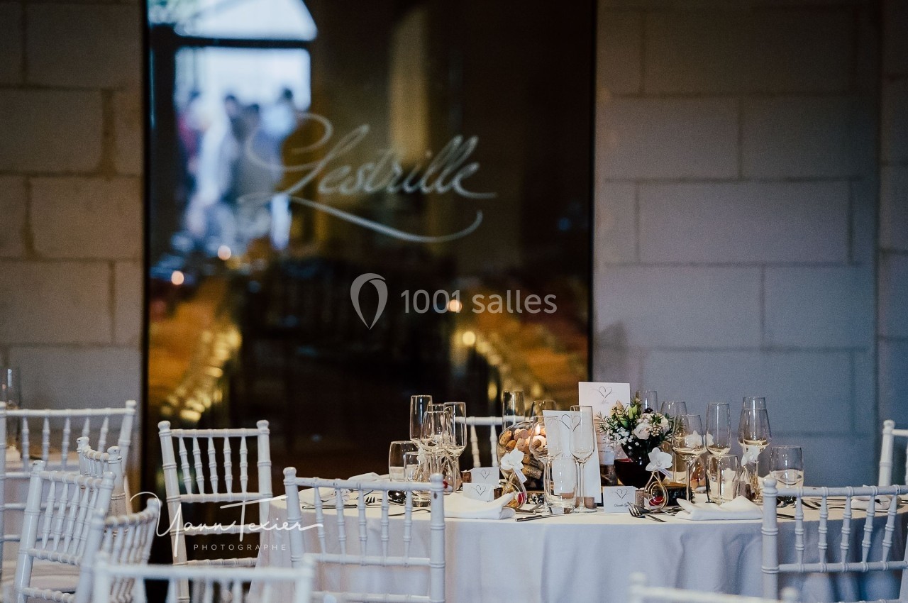 Table élégamment dressée avec décorations florales et vaisselle raffinée devant une vitre portant l'inscription ’Lestrille’.