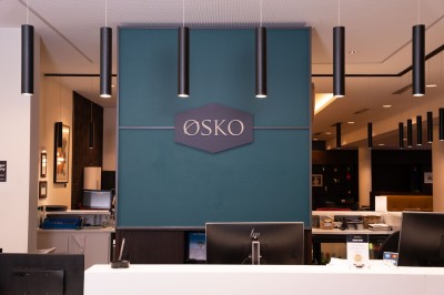 Chambre d'hôtel avec deux lits simples, un fauteuil, un bureau, une lampe et une grande fenêtre avec rideaux.