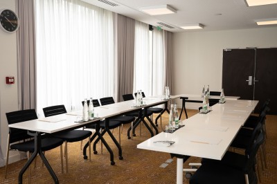 Miniature Location salle Blagnac (Haute-Garonne) - Osko #2 Chambre d'hôtel avec deux lits simples, un fauteuil, un bureau, une lampe et une grande fenêtre avec rideaux.