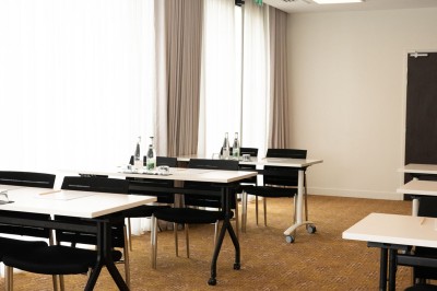 Miniature Location salle Blagnac (Haute-Garonne) - Osko #15 Chambre d'hôtel avec deux lits simples, un fauteuil, un bureau, une lampe et une grande fenêtre avec rideaux.