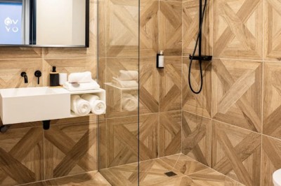 Salle moderne avec murs en briques apparentes, sol en bois et carrelage, écran mural et plante en pot.