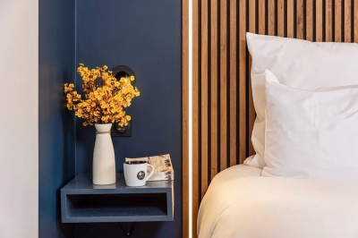 Salle moderne avec murs en briques apparentes, sol en bois et carrelage, écran mural et plante en pot.