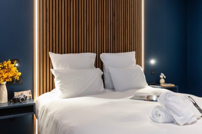 Salle moderne avec murs en briques apparentes, sol en bois et carrelage, écran mural et plante en pot.