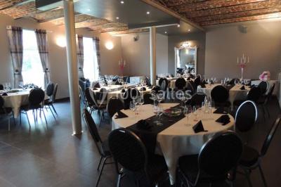 Tente blanche avec toit pointu et bordure rouge installée dans un jardin arboré, entourée de tables et chaises.