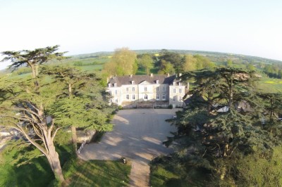 Chambre lumineuse avec lit, bureau en bois, chaise et mur décoré d'un papier peint à motifs végétaux.