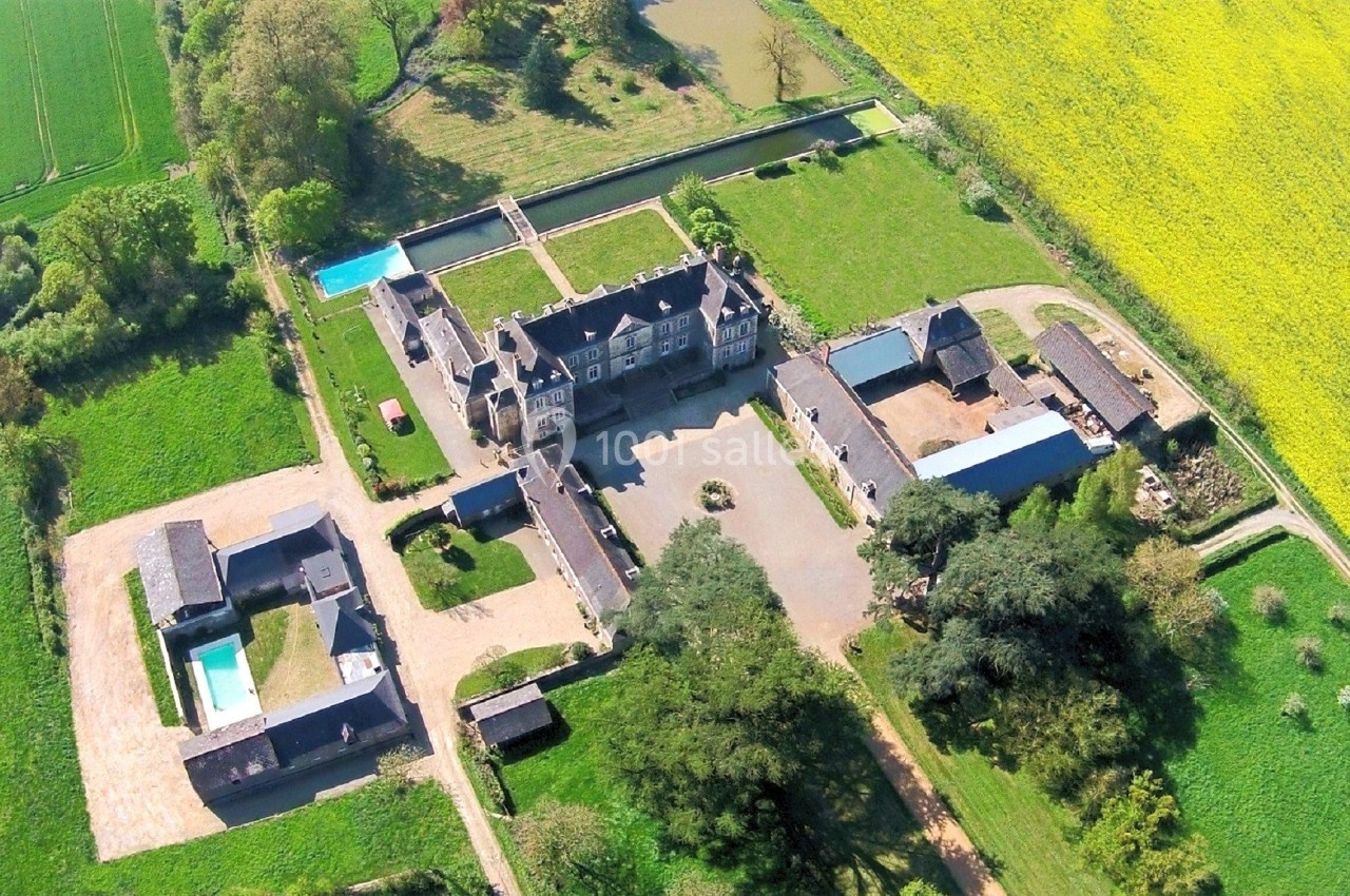 Vue aérienne d'un domaine rural avec bâtiments en pierre, cour centrale, piscine et champs environnants.