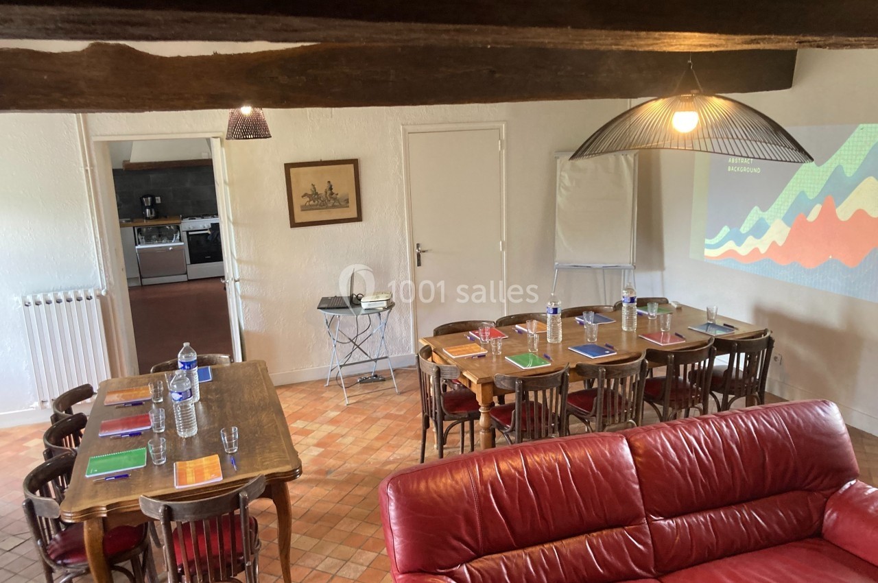 Salle de réunion avec tables en bois, chaises, écran de projection, et fournitures disposées pour une présentation.