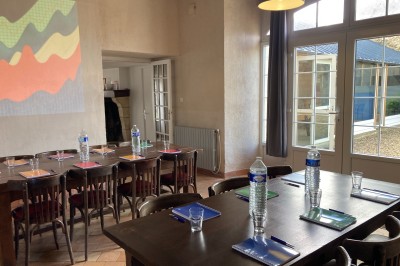 Chambre lumineuse avec lit, bureau en bois, chaise et mur décoré d'un papier peint à motifs végétaux.