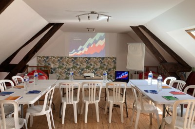 Chambre lumineuse avec lit, bureau en bois, chaise et mur décoré d'un papier peint à motifs végétaux.