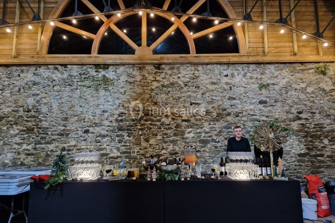 Un bar décoré avec des boissons et des verres, installé devant un mur en pierre dans une salle éclairée.