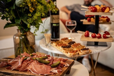Salle chaleureuse avec parquet en bois, tables, chaises, canapés et éclairage tamisé.