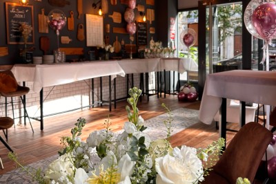 Salle chaleureuse avec parquet en bois, tables, chaises, canapés et éclairage tamisé.