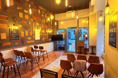 Salle chaleureuse avec parquet en bois, tables, chaises, canapés et éclairage tamisé.