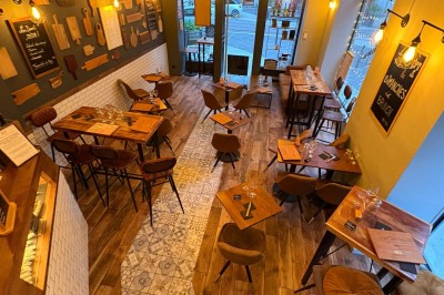 Salle chaleureuse avec parquet en bois, tables, chaises, canapés et éclairage tamisé.
