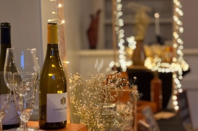 Bouteille de vin blanc et verres sur une table décorée de guirlandes lumineuses et de fleurs séchées.