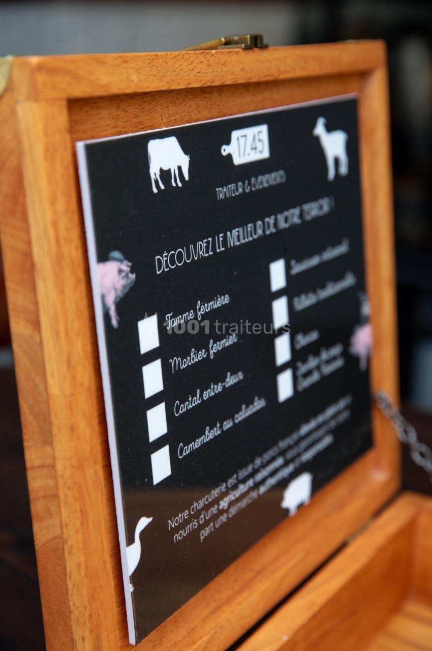 Menu en bois affichant une sélection de fromages fermiers avec illustrations d'animaux et détails des produits.