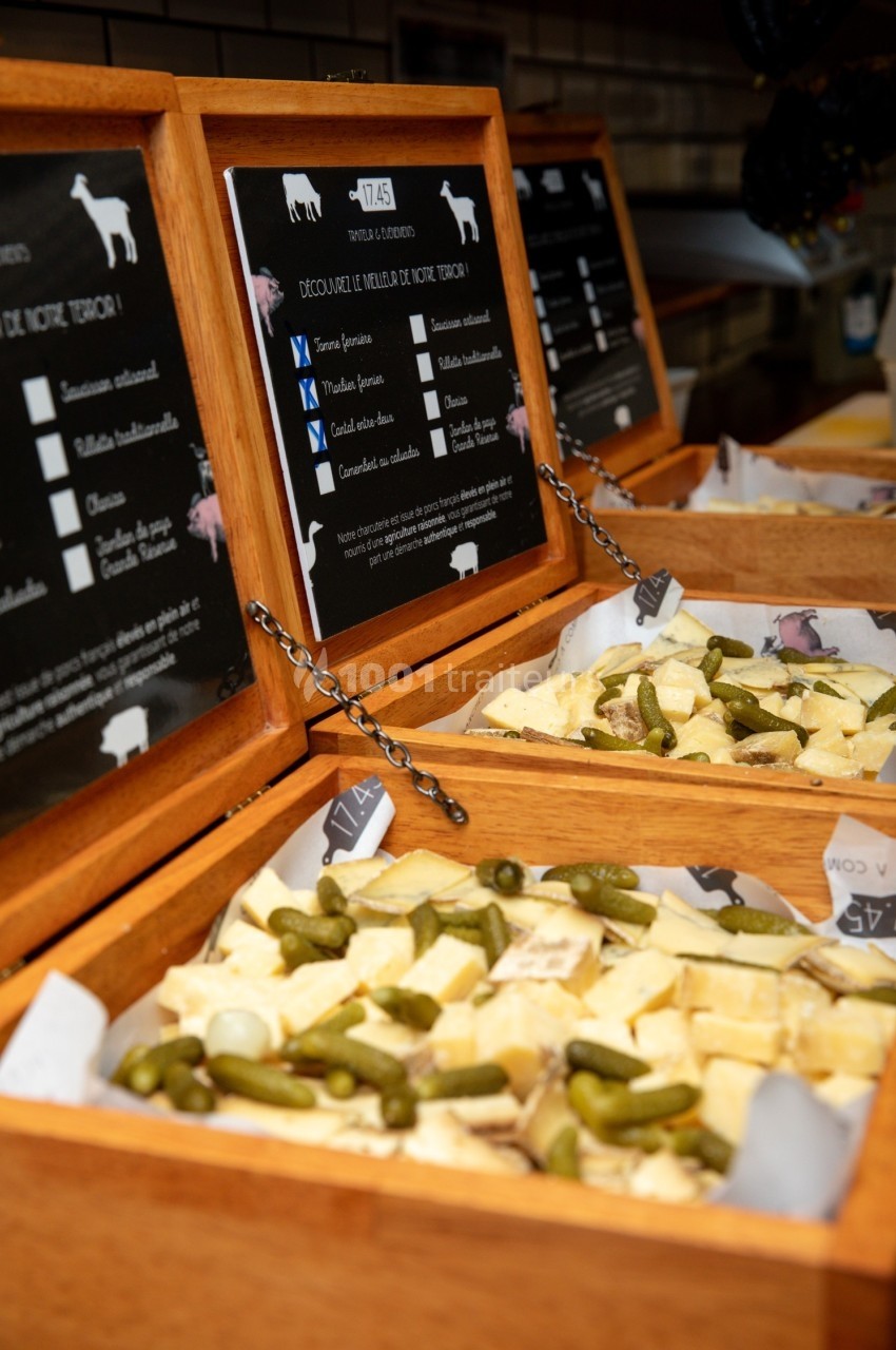Plateau de dégustation avec morceaux de fromage et cornichons présentés dans des boîtes en bois.