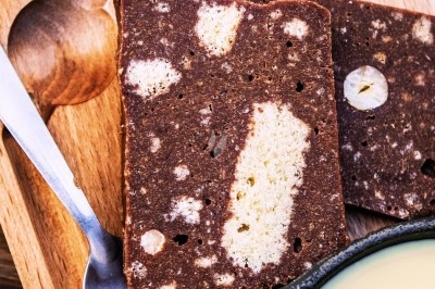 Dessert tiramisu en verrine avec une couche de cacao en poudre sur le dessus, posé sur une ardoise noire.