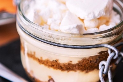 Dessert tiramisu en verrine avec une couche de cacao en poudre sur le dessus, posé sur une ardoise noire.
