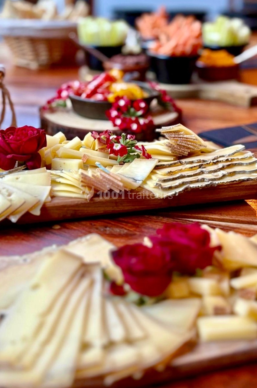 Plateaux de fromages variés avec décorations de roses rouges, disposés sur une table en bois.
