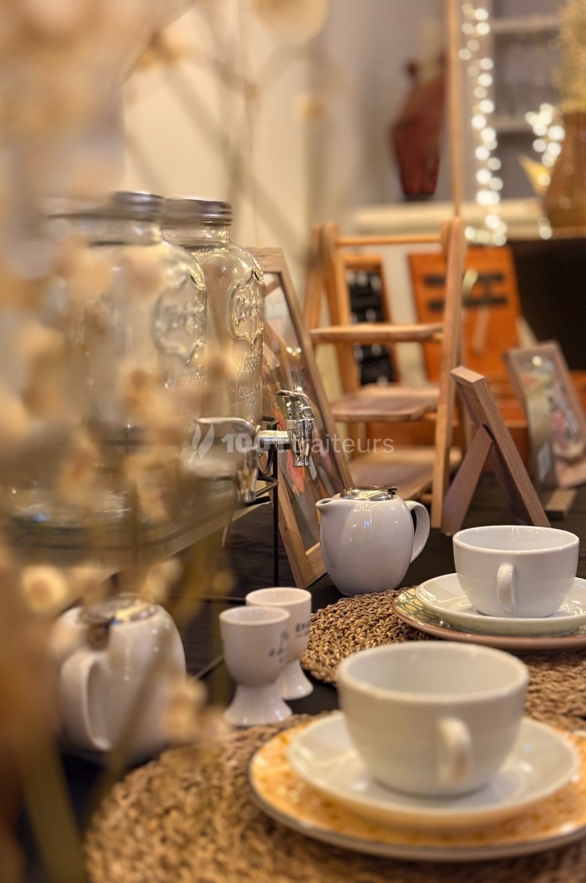Table dressée avec des tasses, théières et distributeurs de boissons, décorée dans un style chaleureux et rustique.