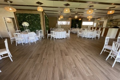 Entrée d'un bâtiment beige avec une toiture rouge, entourée de palissades en bois et d'une pelouse artificielle.