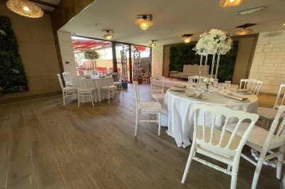 Entrée d'un bâtiment beige avec une toiture rouge, entourée de palissades en bois et d'une pelouse artificielle.