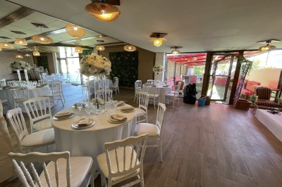 Entrée d'un bâtiment beige avec une toiture rouge, entourée de palissades en bois et d'une pelouse artificielle.