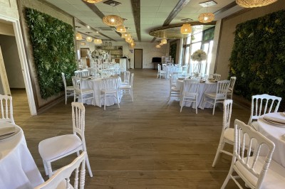 Entrée d'un bâtiment beige avec une toiture rouge, entourée de palissades en bois et d'une pelouse artificielle.