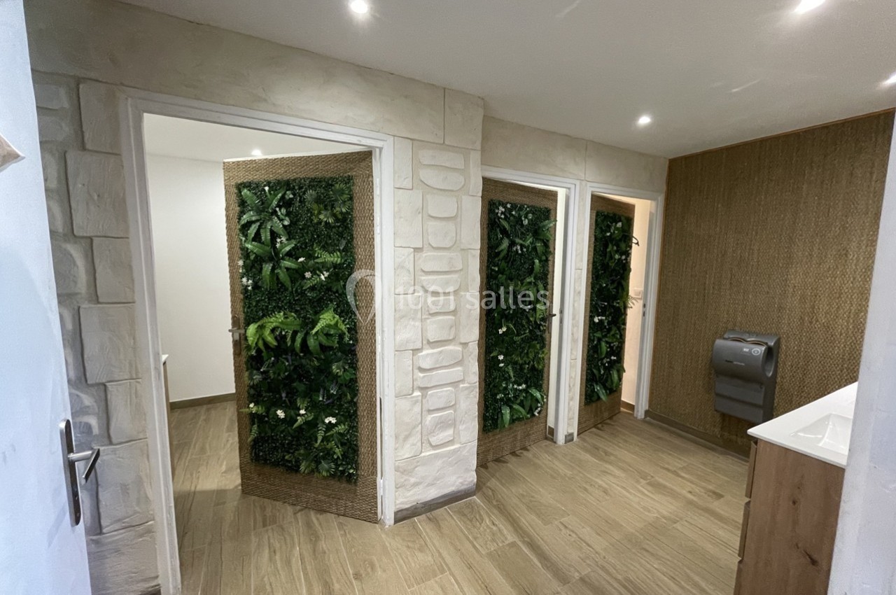 Vue d'un espace intérieur avec des toilettes, murs végétalisés et sol en bois clair.