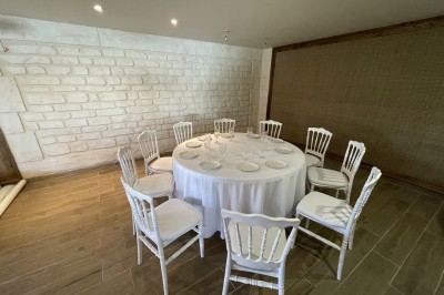 Entrée d'un bâtiment beige avec une toiture rouge, entourée de palissades en bois et d'une pelouse artificielle.