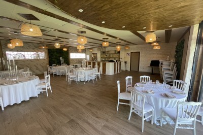 Entrée d'un bâtiment beige avec une toiture rouge, entourée de palissades en bois et d'une pelouse artificielle.