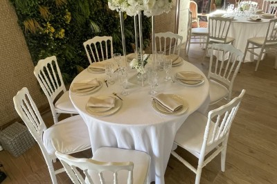 Entrée d'un bâtiment beige avec une toiture rouge, entourée de palissades en bois et d'une pelouse artificielle.